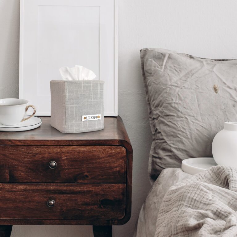 Vertical white picture frame mockup. Retro wooden bedside table. Modern white ceramic vase with dry Lagurus ovatus grass and cup of coffee, beige linen, velvet pillows in Scandinavian bedroom.